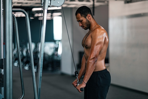 Shirtless Muscular Black Man Training With Crossover Machine At Gym