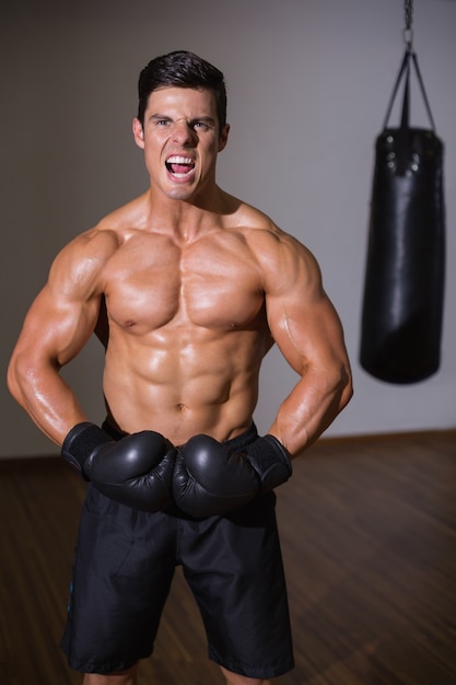 Shirtless muscular boxer shouting in health club