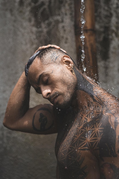 Premium Photo  Cropped of calm afro american male model with closed eyes  and tattoos on muscular arms sitting on floor in isolated studio while  hands of faceless woman with white manicure