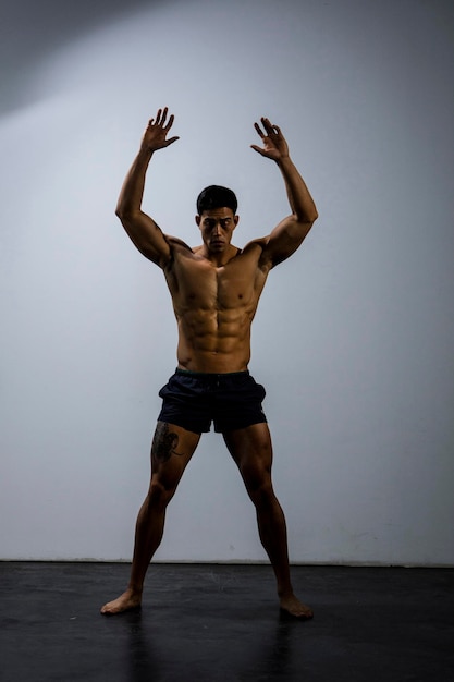 Photo shirtless muscular man exercising against wall