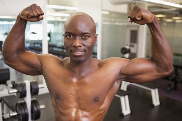 Shirtless muscular man flexing muscles in gym