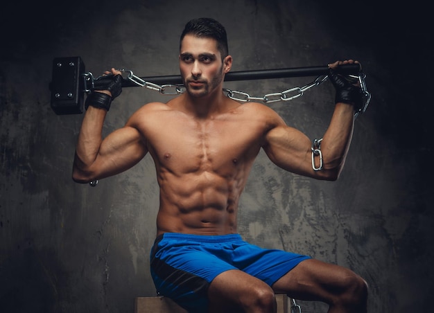 Shirtless muscular man holding a big hammer on his shoulders.