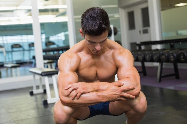 Shirtless muscular man posing in gym