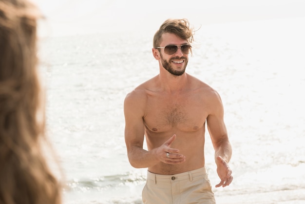 Shirtless muscular tourist walking at the beach in summer