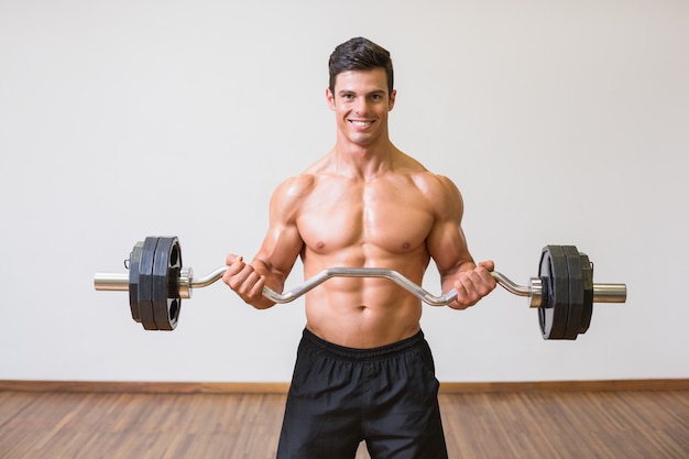 Shirtless spiermens die barbell in gymnastiek opheffen