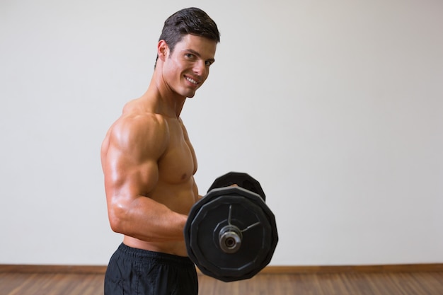 Shirtless spiermens die barbell in gymnastiek opheffen