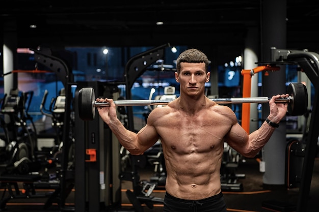 Shirtless strong man lifting barbell in gym weightlifter