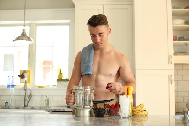 Shirtless teenage boy preparing juice in kitchen at home