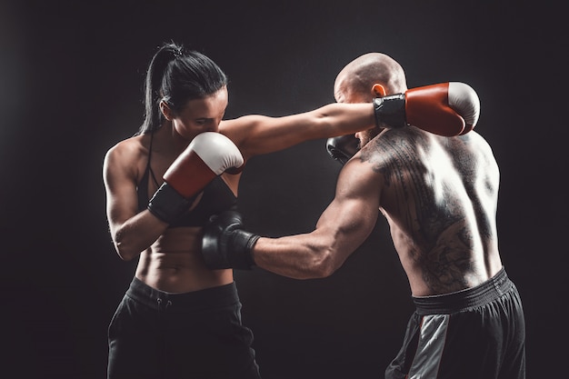 Donna senza camicia che si esercita con l'istruttore alla lezione di boxe e di autodifesa lotta femminile e maschio