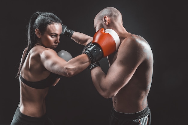 Donna senza camicia che si esercita con l'istruttore alla lezione di boxe e di autodifesa lotta femminile e maschio