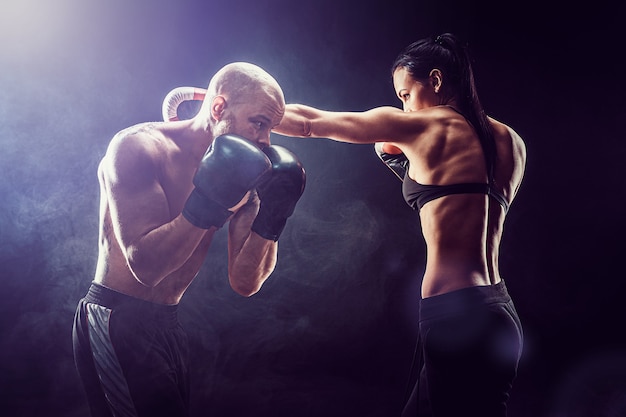 Photo shirtless woman exercising with trainer at boxing