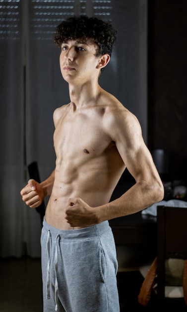 Photo shirtless young man flexing muscles at home