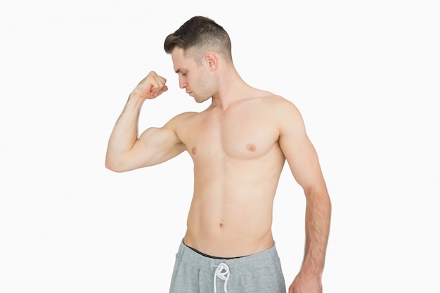 Без рубашки молодой человек сгибает мышцы