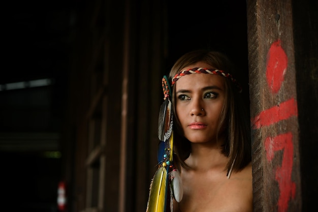 Foto giovane donna senza camicia che guarda lontano mentre si trova accanto a un palo di legno