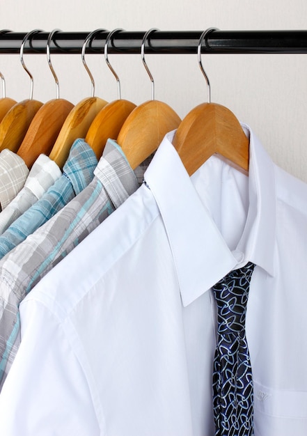 Shirts with ties on wooden hangers on light background