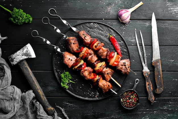 Shish kebab BBQ meat with onions and tomatoes On a black background Top view Free space for your text Rustic style