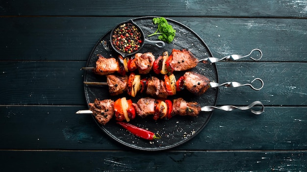 Shish kebab BBQ meat with onions and tomatoes On a black background Top view Free space for your text Rustic style