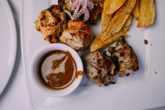 Foto shish kebab e patate fritte carne alla griglia con salse cipolla e patate fritte patatine fritte