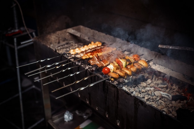 Shish kebab from meat, mushrooms and vegetables are fried on the grill