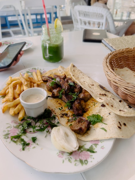 Shish kebab met peterselie in pitabroodje op een bord naast de saus