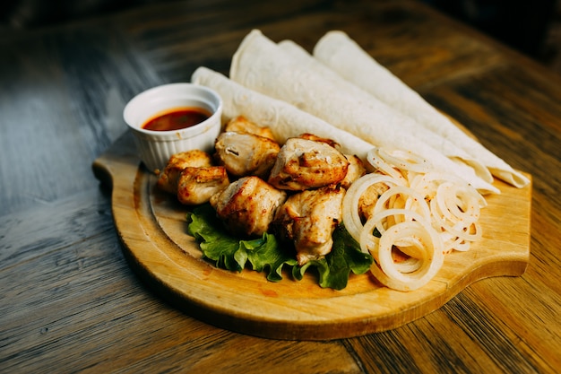 Shish kebab met uiring en lavash op de houten plaat.