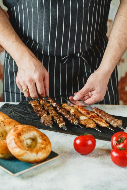Shish kebab of kebab stukjes rundvlees varkensvlees of kip op spiesjes gekookt op de grill in de handen van de chef-kok Traditioneel gerecht uit de Kaukasische en Aziatische keuken