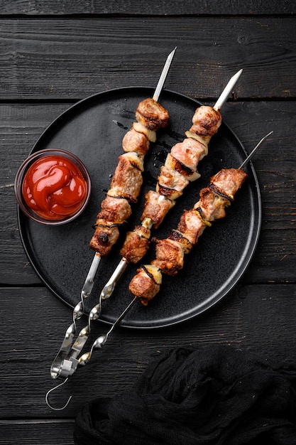 Shish kebab of pork set, on black wooden table background, top view flat lay, with copy space for text