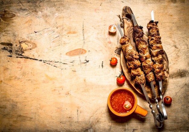 Shish kebab with tomato sauce. On a wooden table.