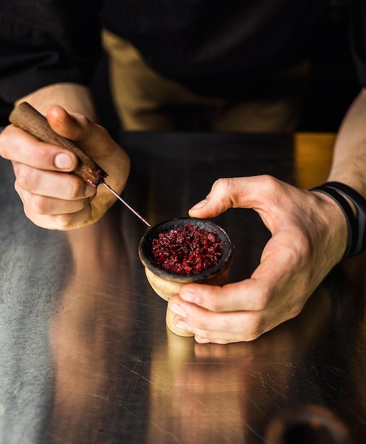 Shisha narghilè preparando dal barman il barista posa il tabacco per fumare