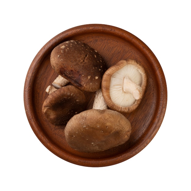 Shitake mushrooms on a wooden plate isolated over white surface.