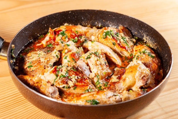 Photo shkmeruli chicken in garlic sauce on a frying pan