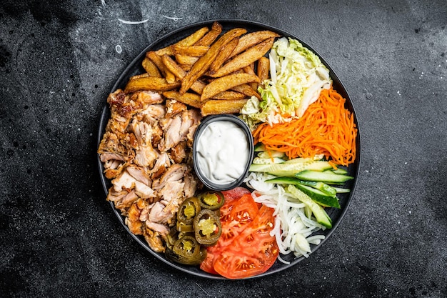 Shoarma Döner kebab op een bord met frietjes en salade Zwarte achtergrond Bovenaanzicht