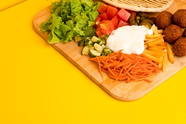 Shoarma met falafel op een houten plank zijaanzicht op een gele achtergrond