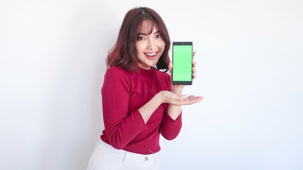 Shock Asian beautiful girl point on green screen phone in white background