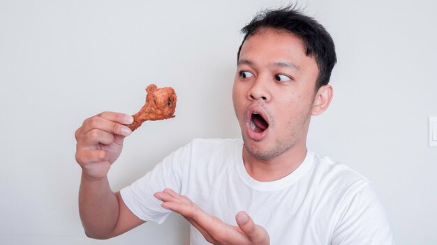 Shock and Wow face of Young Asian man is eating fried chicken wear white shirt