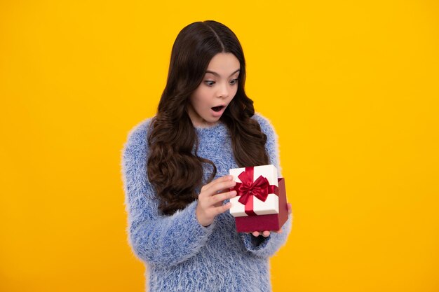 Shocked amazed face surprised emotions of young teenager girl Funny kid girl in winter wear holding gift boxes celebrating happy New Year or Christmas Winter holiday