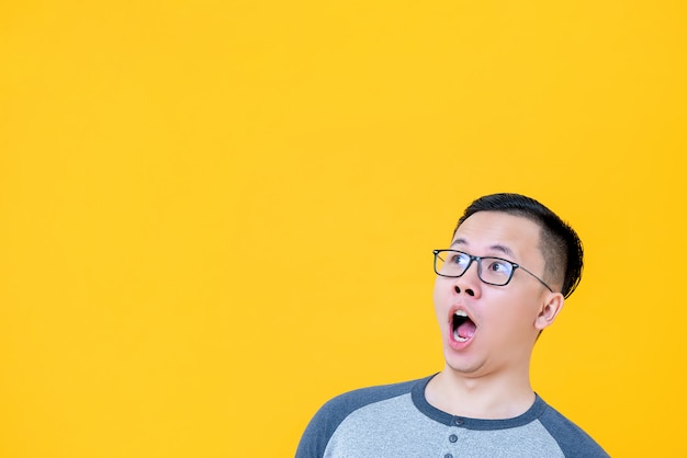 Shocked Asian man gasping and looking to copy space aside