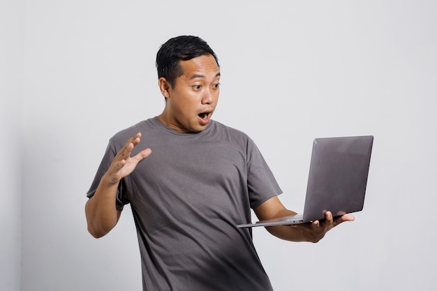 Shocked Asian man looking at laptop