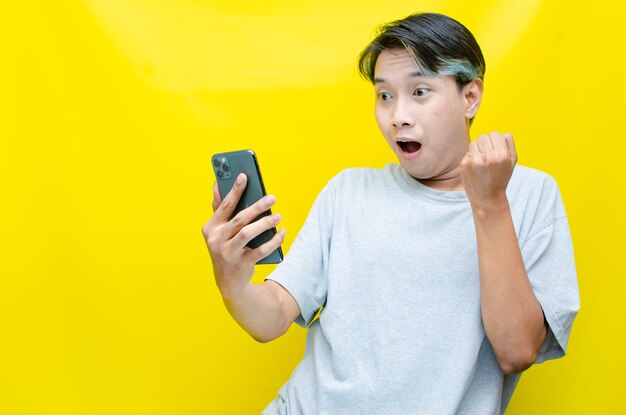 A shocked asian man in peekaboo hair holding the phone and receiving good news