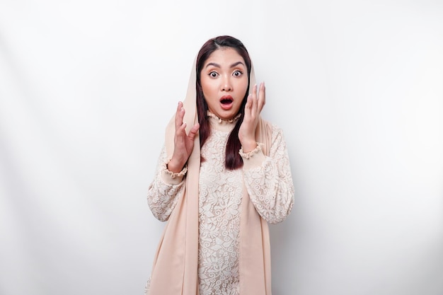 Shocked Asian Muslim woman wearing headscarf with her mouth wide open isolated by white background