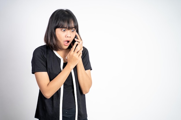 Shocked asian woman making a call using a cell phone