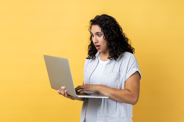 Shocked astonished woman working on laptop looking at screen with big eyes and open mouth