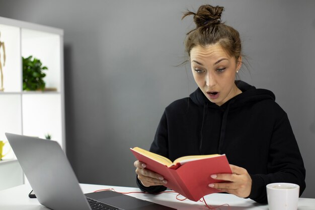 Shocked beautiful girl reading book during quarantine. Self-education