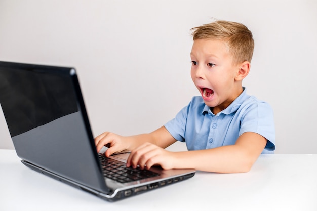 Shocked boy using laptop with open mouth