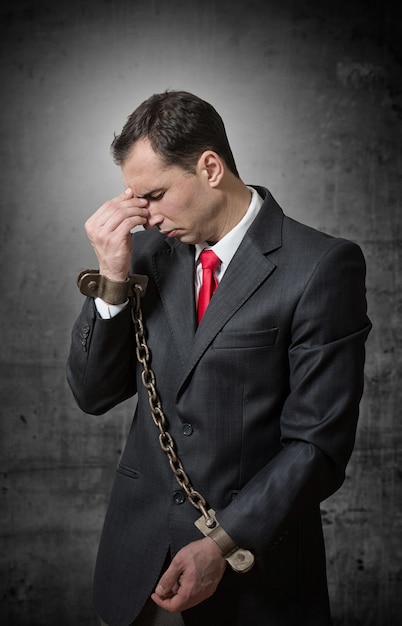 Shocked businessman with chained hands