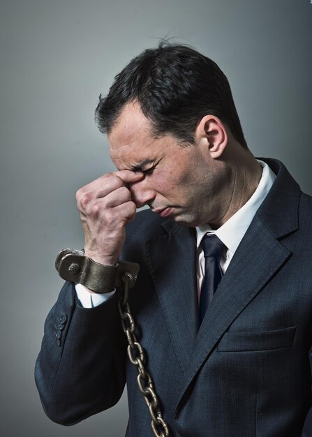 Shocked businessman with chained hands