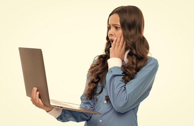 Foto capelli ricci lunghi del bambino scioccato che digitano sul computer portatile isolato sull'istruzione bianca