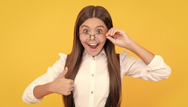 Shocked child long hair look like nerd thumb up teen girl look through eyeglasses