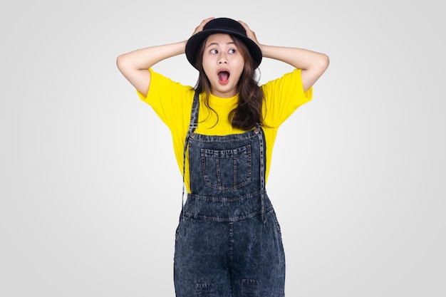 Shocked Cute Asian girl in yellow and black hat with white background