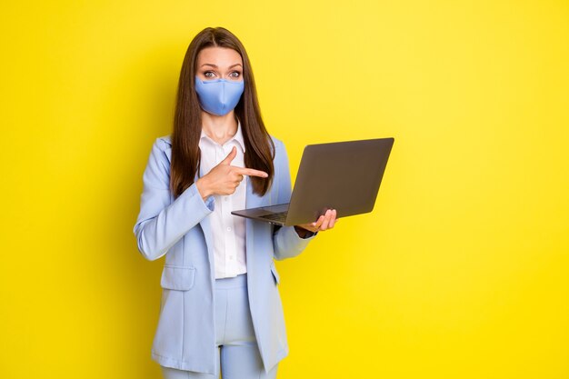 Shocked economist girl in respiratory mask work remote point finger laptop present covid quarantine news wear blue blazer jacket pants trousers isolated bright shine color background